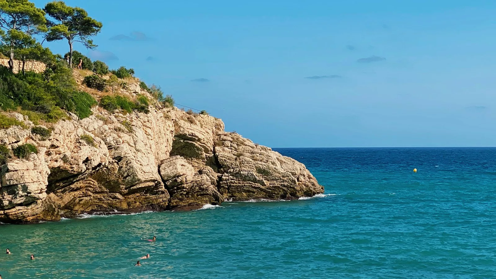 Muntanya rocosa marró al costat del mar blau sota el cel blau durant el dia